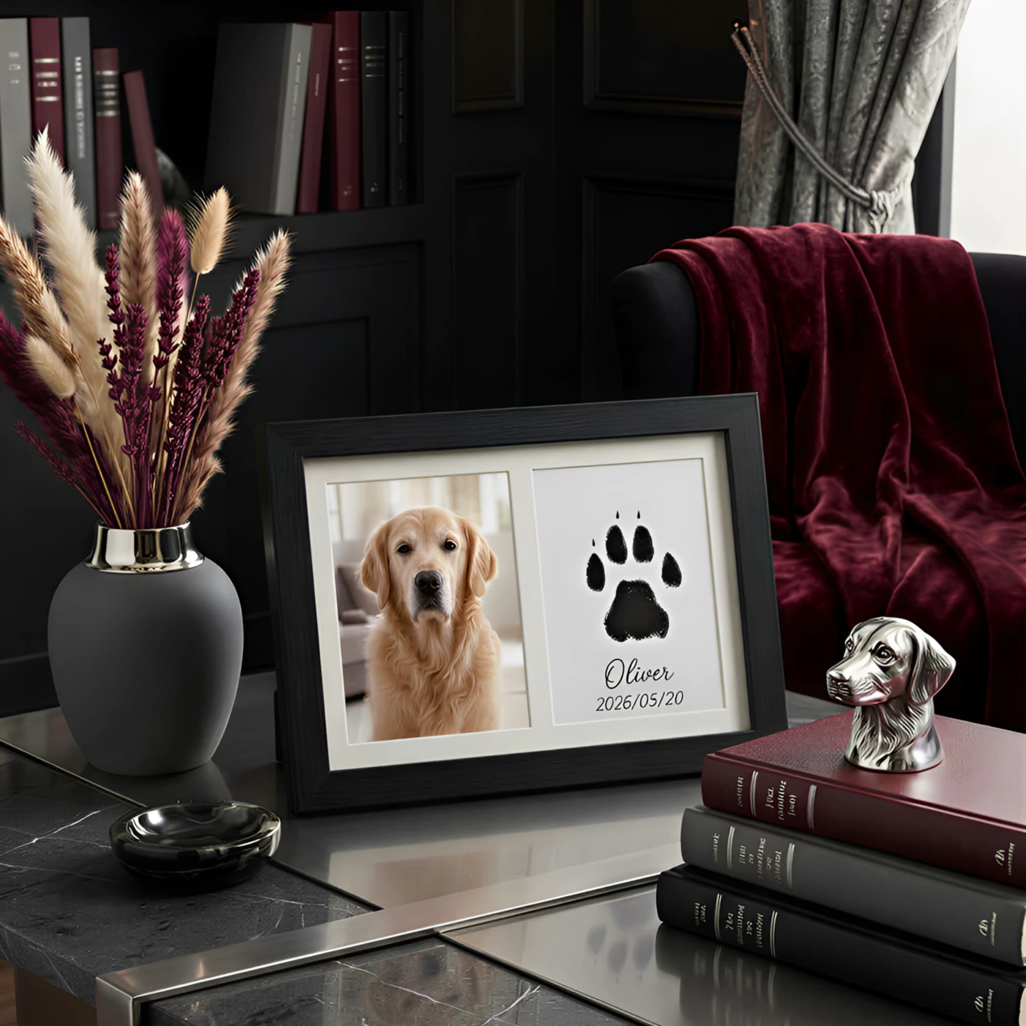 A black double frame holding a photo of Oliver the golden retriever beside his paw print, on a marble table in a dark living room